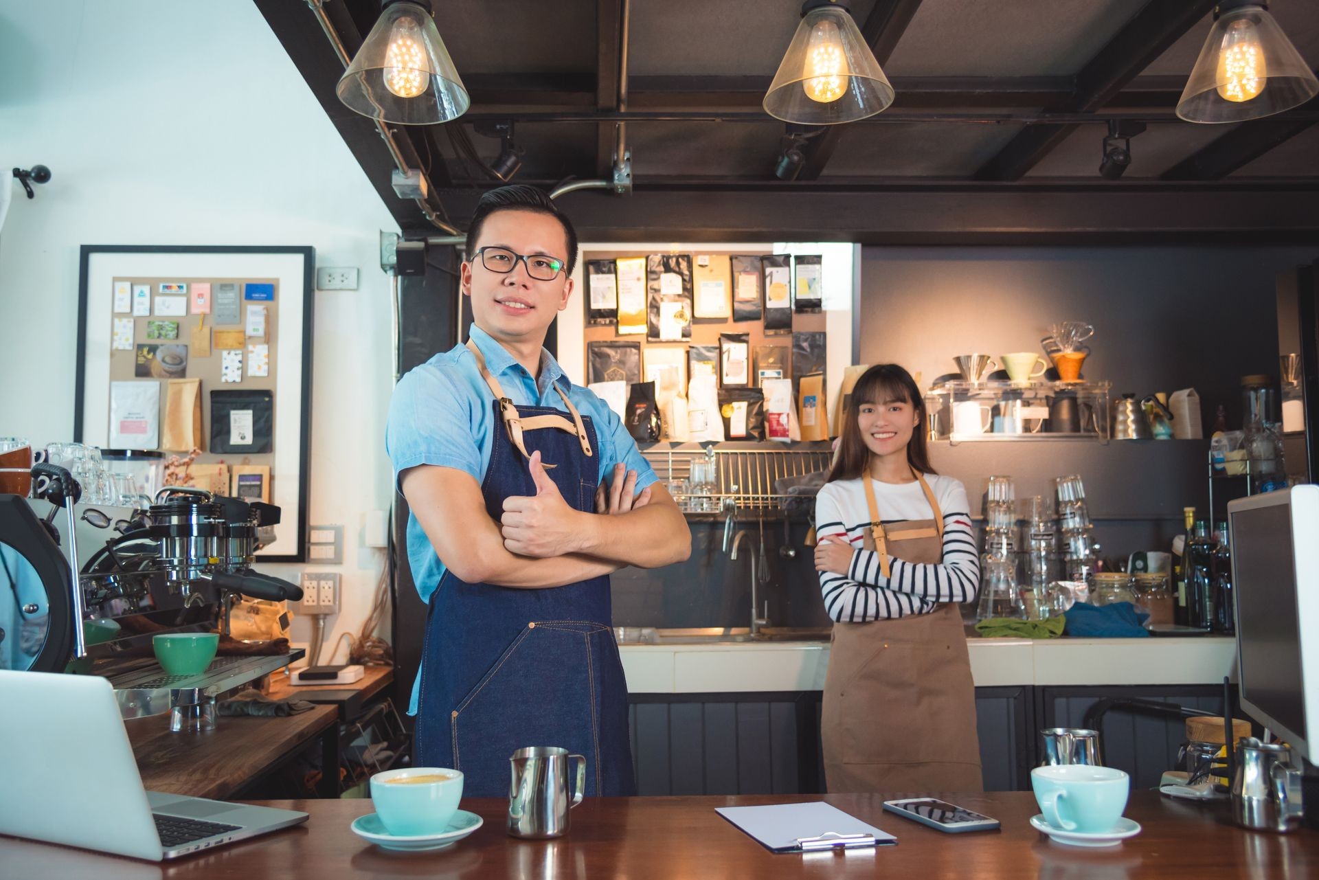 Young Asian barista standing with smile in their coffee shop